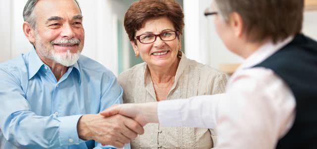 senior couple smiling while shaking hand with financial advisor